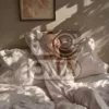 Изображение девушка сидит в пижаме на кровати с подушками
